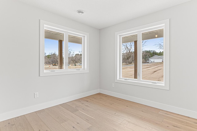 unfurnished room featuring light wood-style flooring, baseboards, and a healthy amount of sunlight