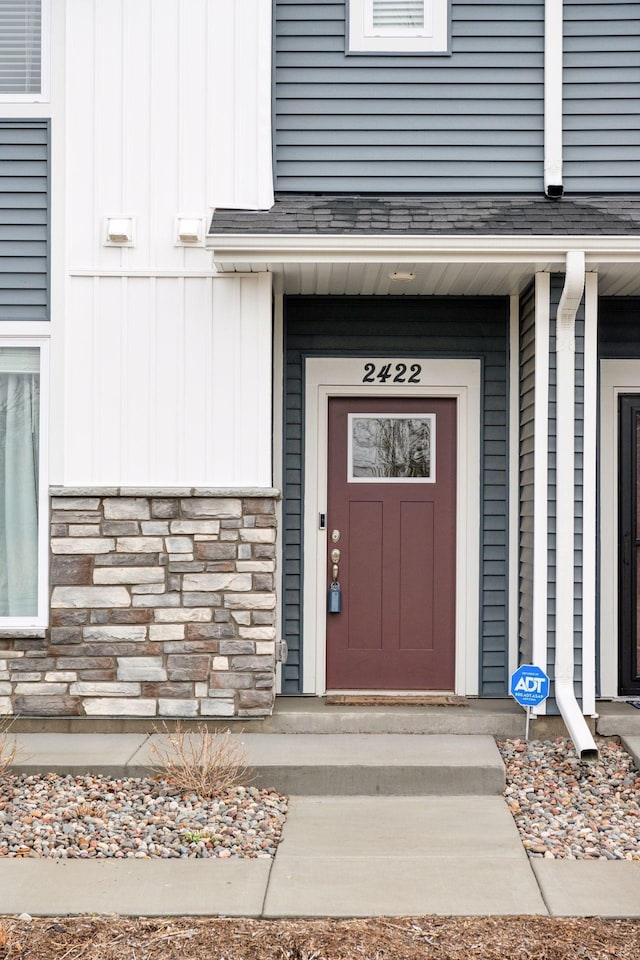 property entrance with board and batten siding and stone siding
