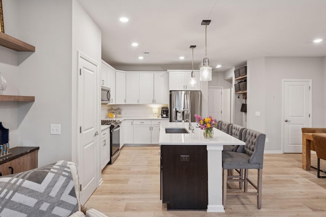 kitchen with a kitchen bar, recessed lighting, light countertops, a sink, and appliances with stainless steel finishes