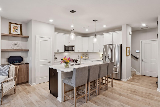 kitchen featuring a sink, light wood-style floors, light countertops, stainless steel appliances, and white cabinetry