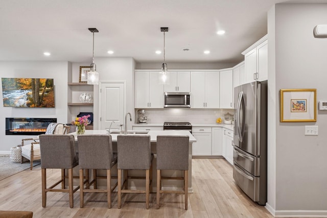 kitchen with light wood-type flooring, light countertops, white cabinetry, a sink, and stainless steel appliances