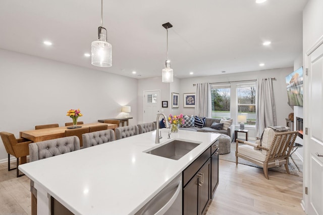 kitchen featuring a sink, light countertops, open floor plan, light wood-style floors, and recessed lighting