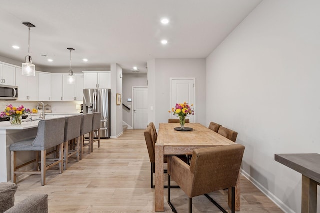 dining space with light wood-type flooring, recessed lighting, and baseboards