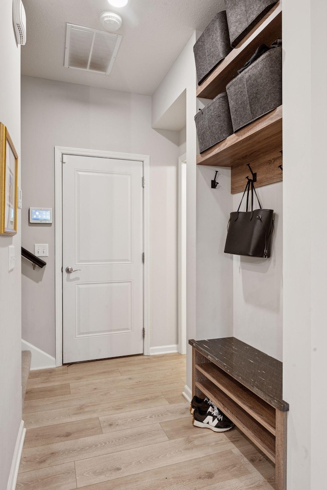 mudroom with baseboards, light wood-style flooring, and visible vents