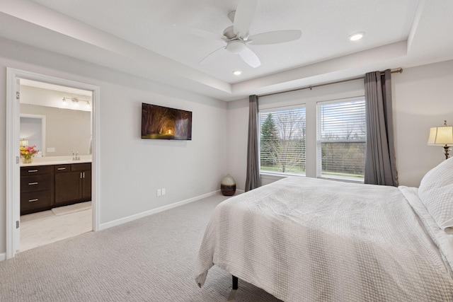 bedroom featuring light carpet, baseboards, recessed lighting, a raised ceiling, and a sink