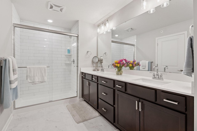 bathroom featuring a sink, double vanity, marble finish floor, a shower stall, and visible vents