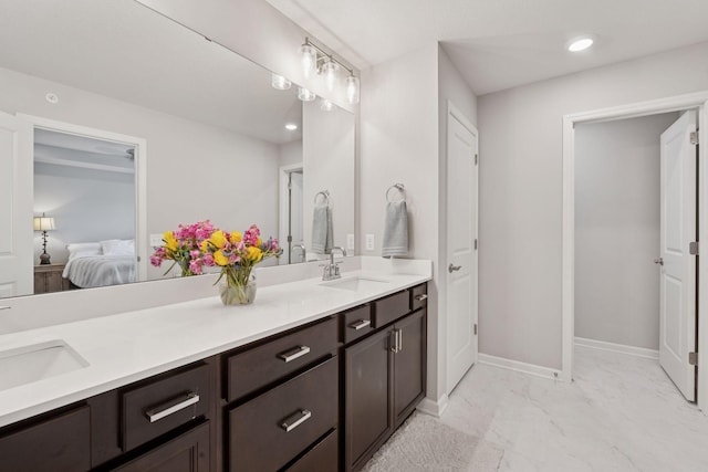 ensuite bathroom featuring double vanity, a sink, connected bathroom, and recessed lighting