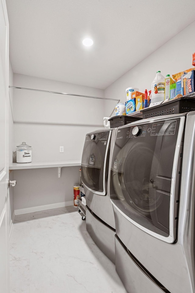 clothes washing area with laundry area, baseboards, and washing machine and dryer