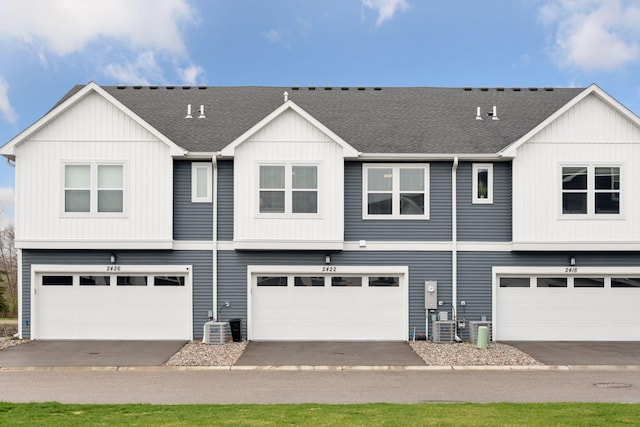multi unit property featuring central air condition unit, a shingled roof, and a garage