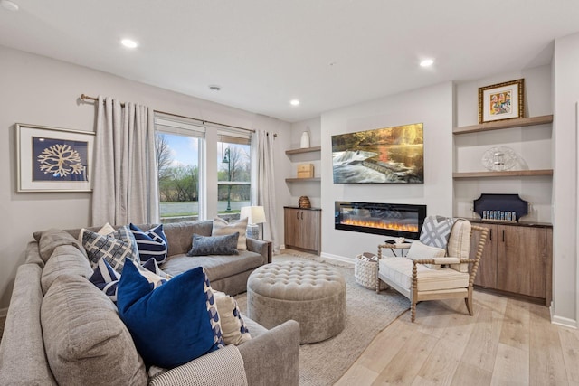 2422 Blossom Cir, Orono, MN 55356 - living room featuring light wood finished floors, a glass covered fireplace, recessed lighting, built in shelves, and baseboards