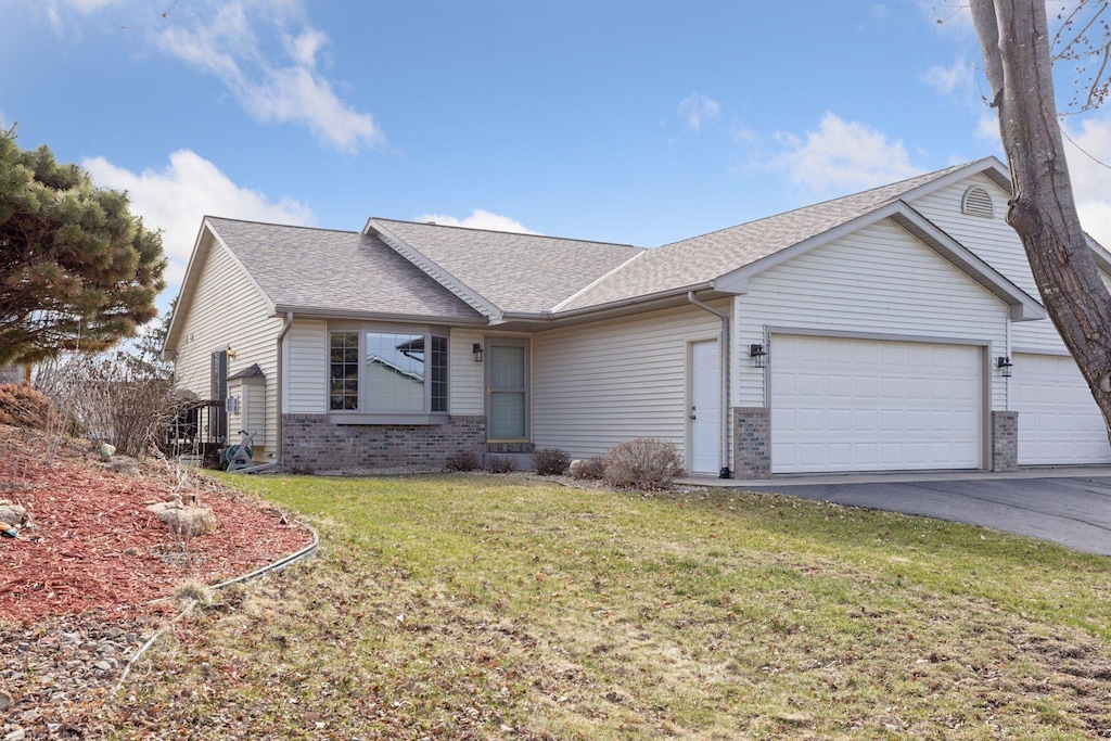 ranch-style home featuring a front lawn, aphalt driveway, brick siding, a garage, and a shingled roof
