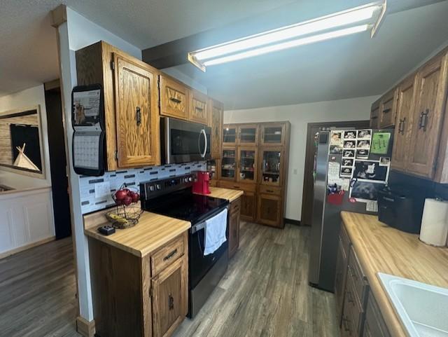 kitchen featuring stainless steel appliances, a sink, decorative backsplash, and wood finished floors