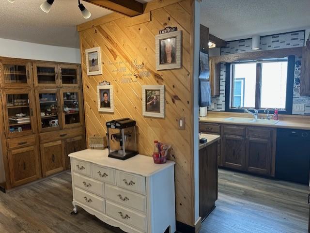 interior space with a textured ceiling, wood finished floors, wood walls, and a sink