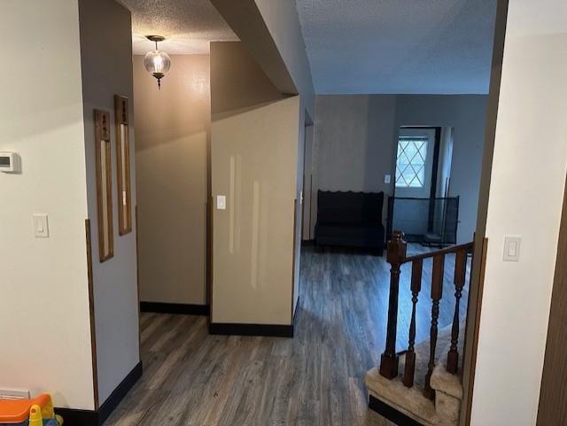 hall featuring baseboards, stairs, wood finished floors, and a textured ceiling