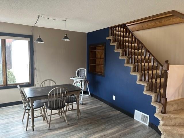 dining room featuring stairs, visible vents, baseboards, and wood finished floors