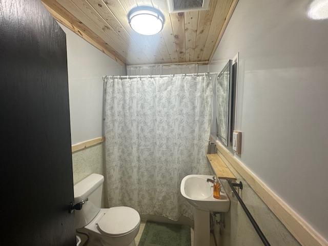 bathroom with visible vents, toilet, curtained shower, and wood ceiling