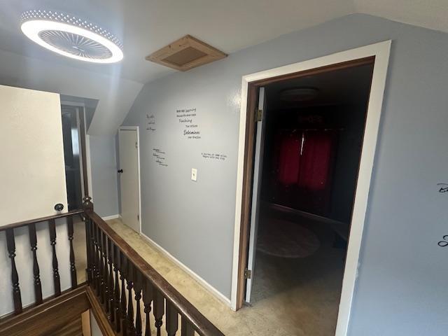 corridor with an upstairs landing and vaulted ceiling