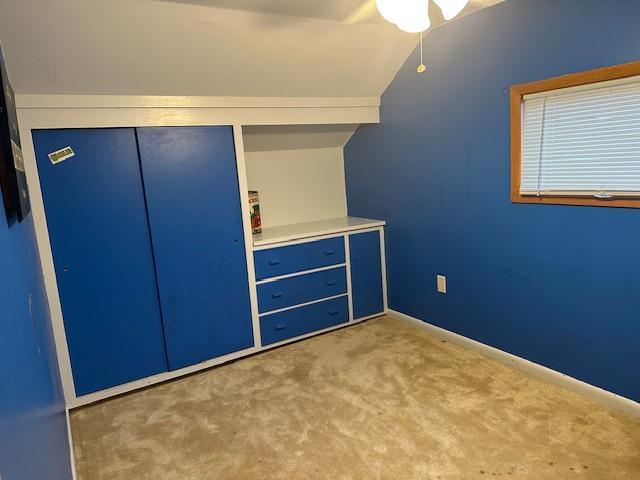 unfurnished bedroom with a closet, a ceiling fan, vaulted ceiling, carpet flooring, and baseboards