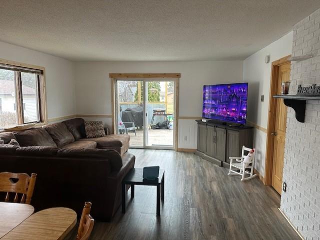 living area featuring a healthy amount of sunlight, wainscoting, a textured ceiling, and wood finished floors