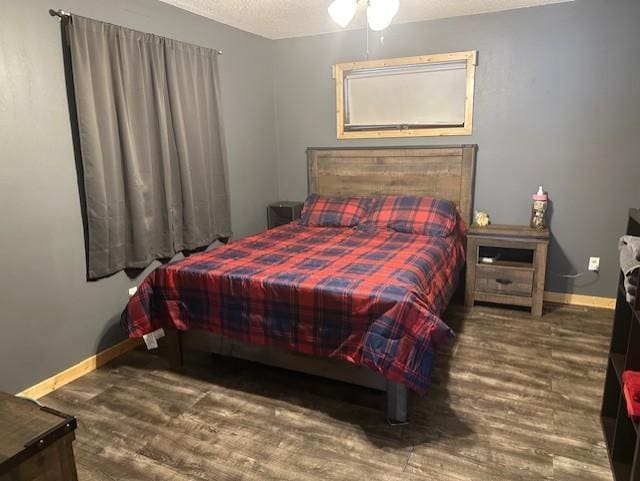 bedroom featuring a textured ceiling, wood finished floors, and baseboards