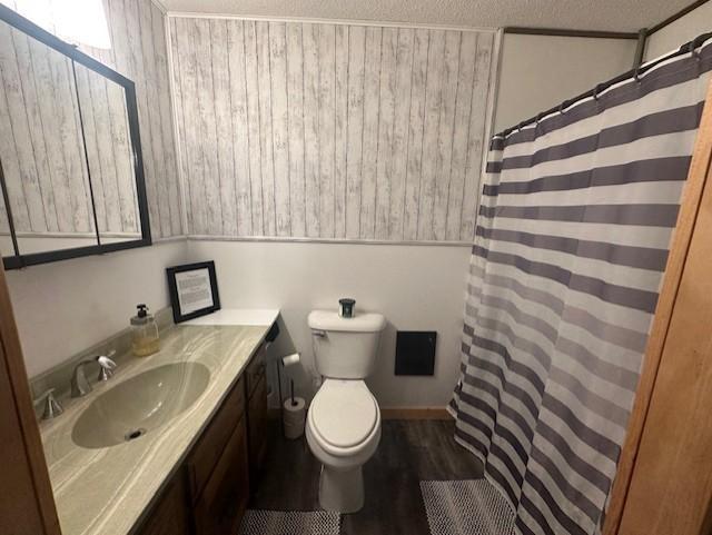 full bath with a textured ceiling, vanity, toilet, wood finished floors, and a shower with shower curtain