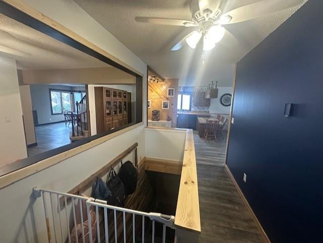 stairs featuring baseboards, a textured ceiling, a ceiling fan, and wood finished floors