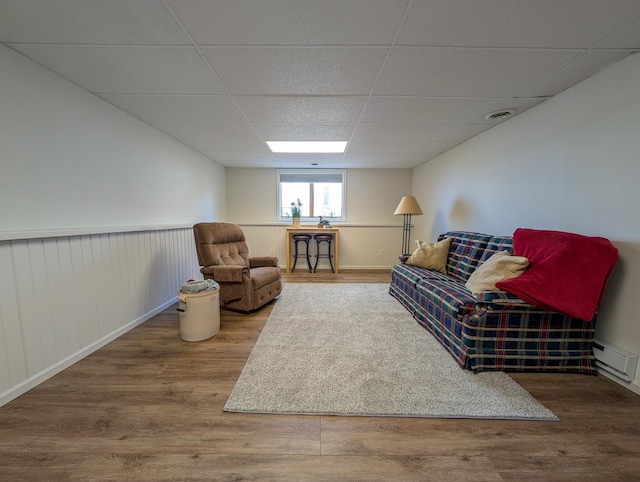 45257 Jack Pine Dr, Perham Twp, MN 56573 - living area with a drop ceiling, wood finished floors, baseboard heating, and a wainscoted wall