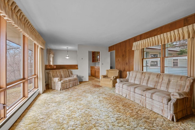 living area featuring a baseboard radiator, a wealth of natural light, carpet flooring, and wood walls