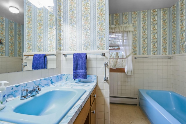 full bath featuring a baseboard heating unit, tile walls, a bathing tub, wallpapered walls, and vanity