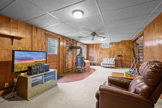 living room with a wood stove, a wealth of natural light, carpet flooring, and wooden walls