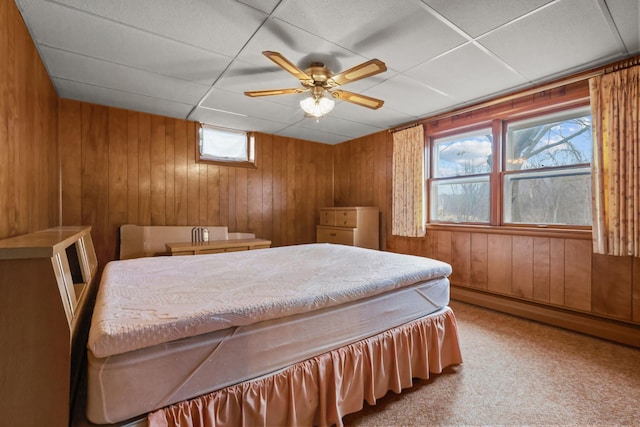 bedroom featuring wood walls, carpet floors, a baseboard radiator, and a drop ceiling