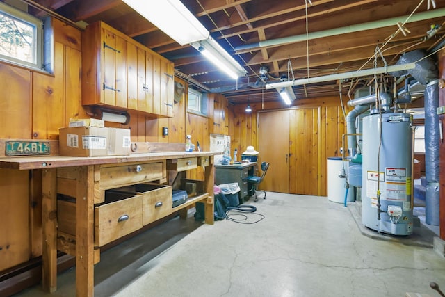 basement with water heater, wooden walls, and a workshop area