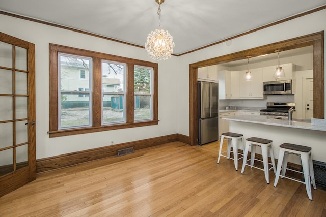 kitchen featuring white cabinetry, visible vents, light countertops, appliances with stainless steel finishes, and ornamental molding