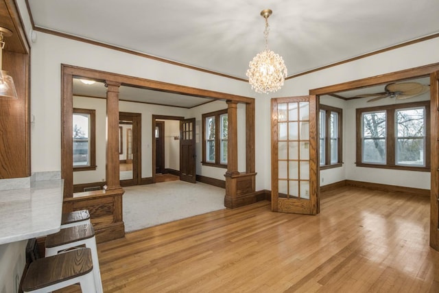 interior space featuring crown molding, light wood-type flooring, baseboards, and decorative columns