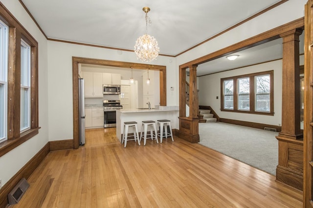 dining room with ornamental molding, visible vents, decorative columns, and light wood-style floors