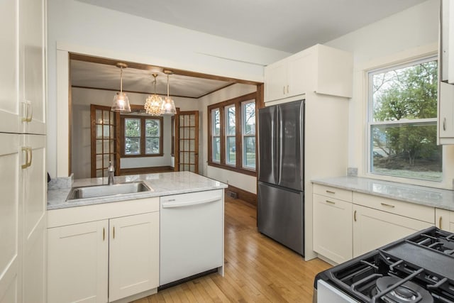 kitchen with a sink, freestanding refrigerator, dishwasher, light wood-style floors, and a chandelier