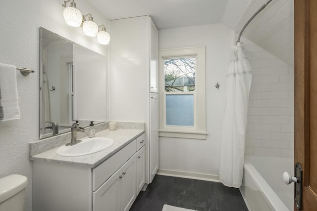 bathroom featuring vanity, toilet, baseboards, and shower / bath combo