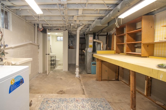 below grade area featuring heating unit, a workshop area, electric panel, concrete block wall, and washer / clothes dryer