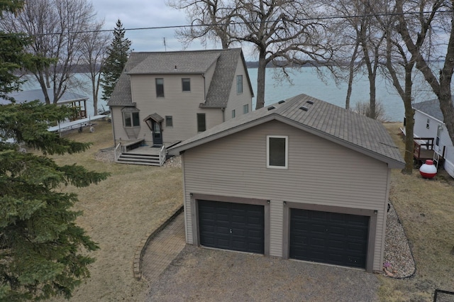 7030 147th Ave SE, Lake Lillian, MN 56253 - back of house featuring gravel driveway, a garage, roof with shingles, and a water view