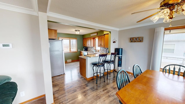 7030 147th Ave SE, Lake Lillian, MN 56253 - dining area with ceiling fan, crown molding, light wood finished floors, baseboards, and a textured ceiling