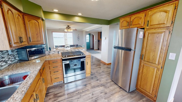 7030 147th Ave SE, Lake Lillian, MN 56253 - kitchen with appliances with stainless steel finishes, arched walkways, light wood-style floors, a sink, and a ceiling fan