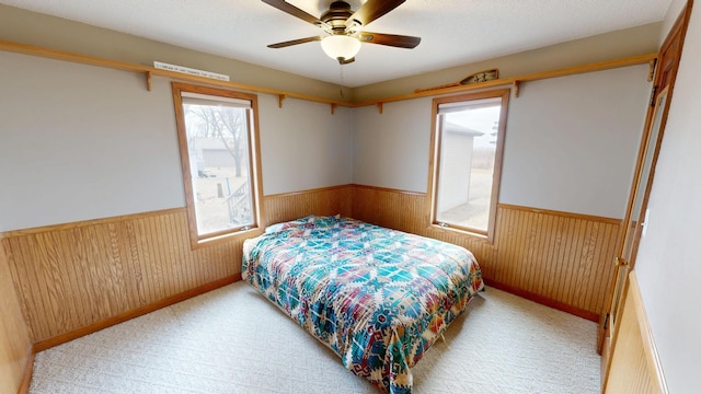 7030 147th Ave SE, Lake Lillian, MN 56253 - carpeted bedroom featuring wainscoting, wood walls, and ceiling fan