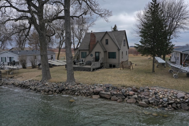 7030 147th Ave SE, Lake Lillian, MN 56253 - view of front of property featuring a deck with water view, a front lawn, central air condition unit, and a shingled roof
