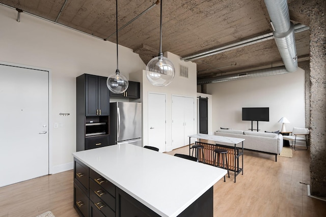 kitchen with visible vents, light countertops, freestanding refrigerator, light wood-style floors, and pendant lighting