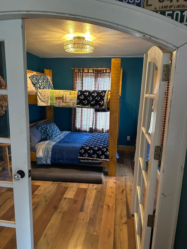 bedroom with hardwood / wood-style floors, multiple closets, and a textured ceiling