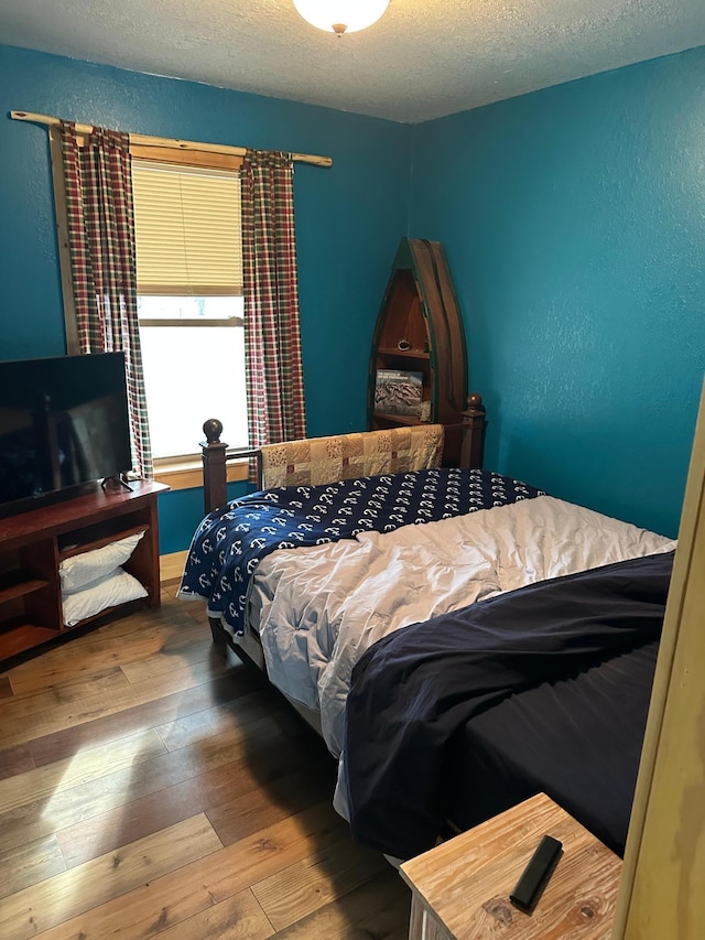 bedroom with a textured wall, a textured ceiling, and wood-type flooring