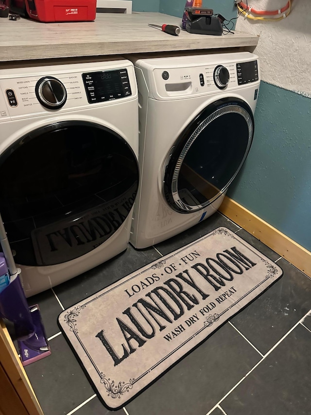 laundry room featuring baseboards, tile patterned flooring, washer and clothes dryer, and laundry area