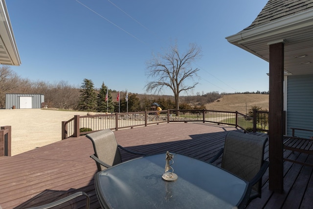 3195 115th St NW, Oronoco, MN 55960 - wooden deck with outdoor dining area, a storage unit, an outdoor structure, and a rural view