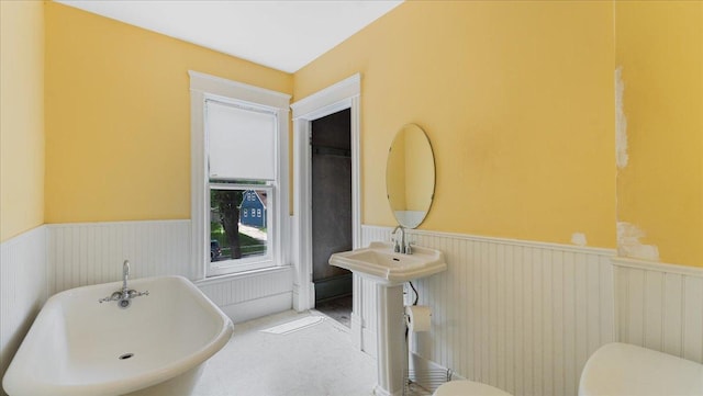 723 3rd St SW, Willmar, MN 56201 - full bathroom with wainscoting, a soaking tub, toilet, and tile patterned floors