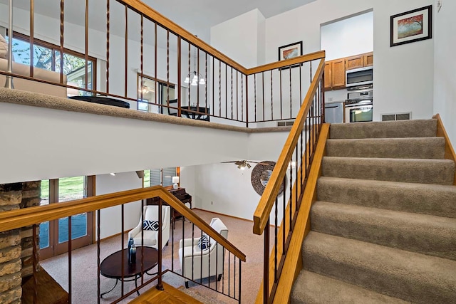 stairs with carpet floors, healthy amount of natural light, a towering ceiling, and baseboards